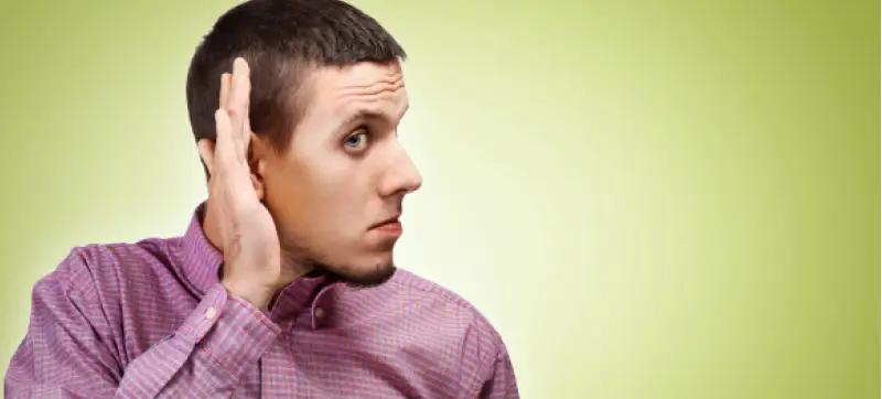 A man listening for noise with his hand to his ear