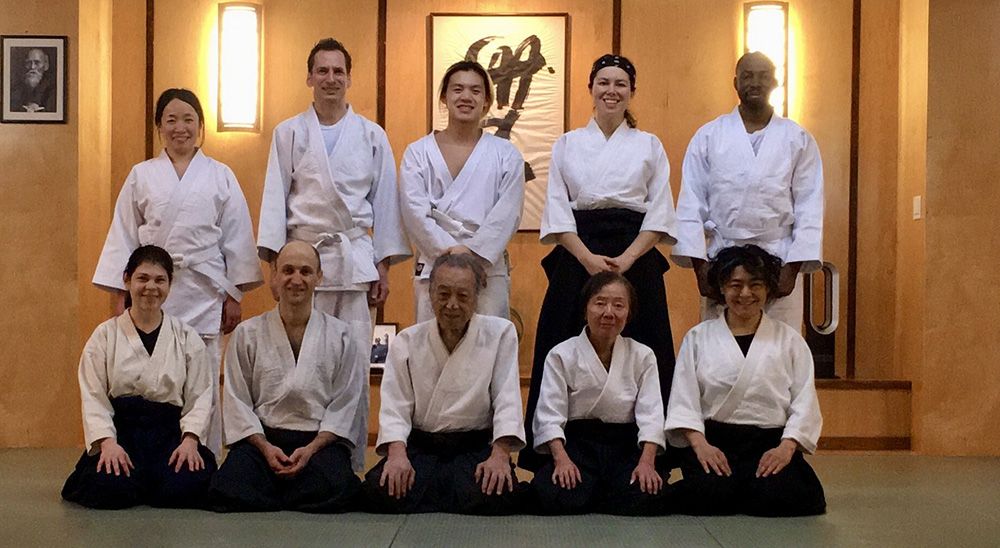 A group of Aikido students posing for a photo in a dojo.