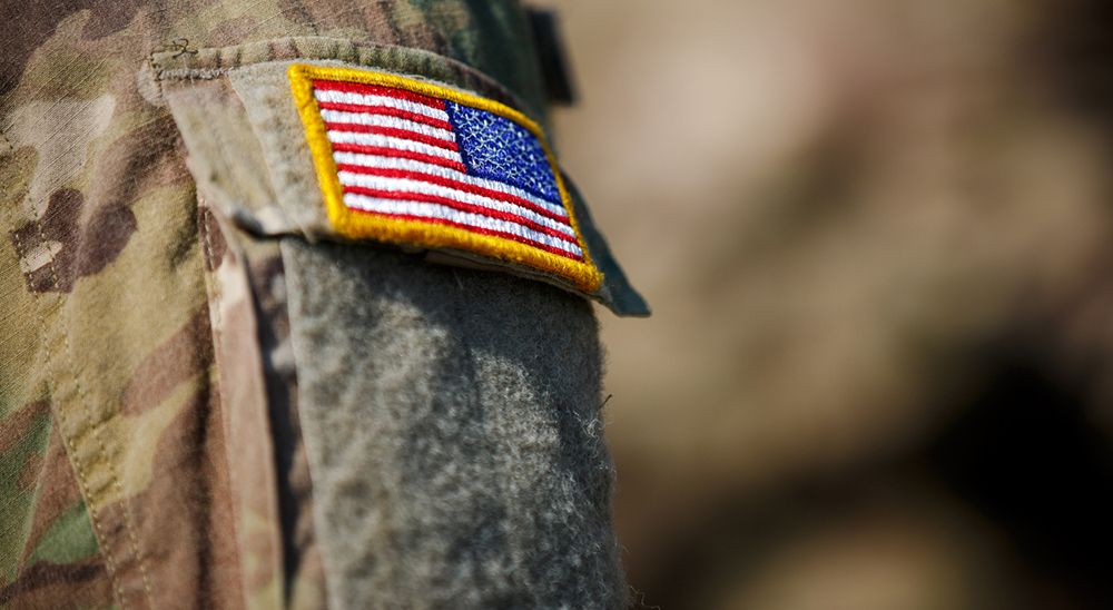 A close-up of the arm of a military uniform with an American flag patch.