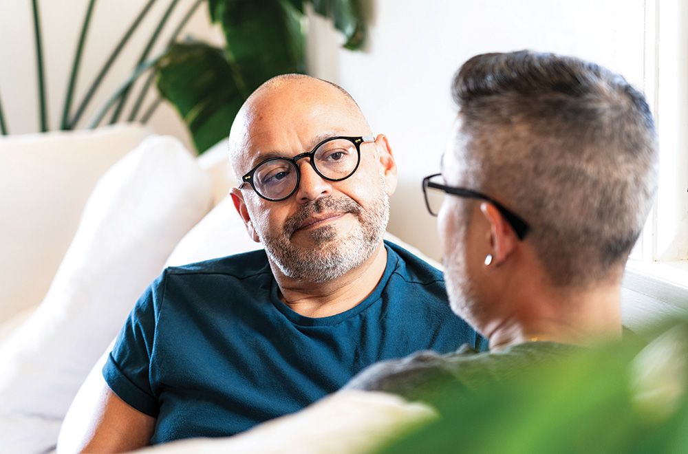 Two men sit on a couch, talking