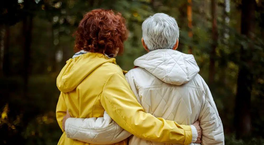 Two people facing away from the camera, with their arms around each other.