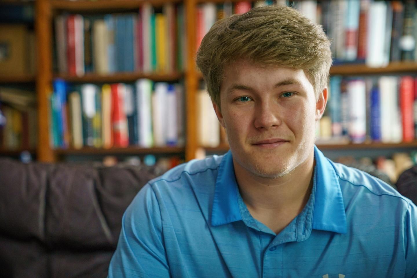 A young man who lives with MS sits in his college library.