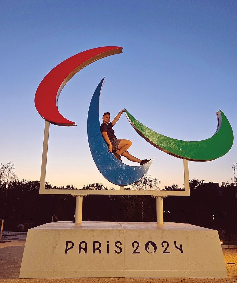 Rachel Watts sits on a "Paris 2024" sign