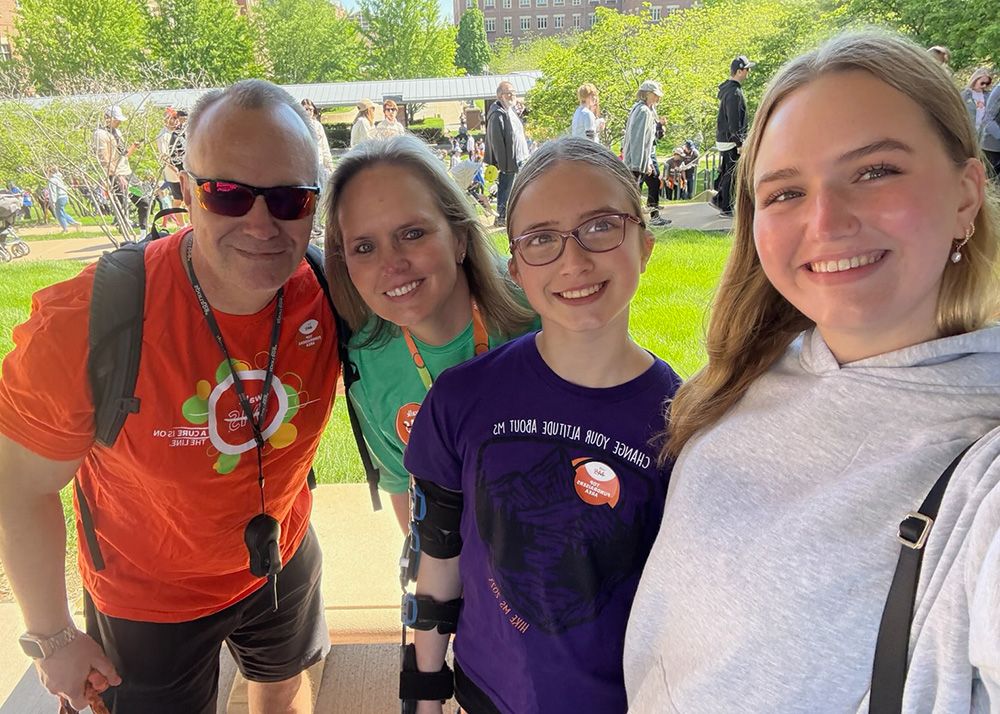 A couple and their two daughters smile outdoors during a Walk MS event.