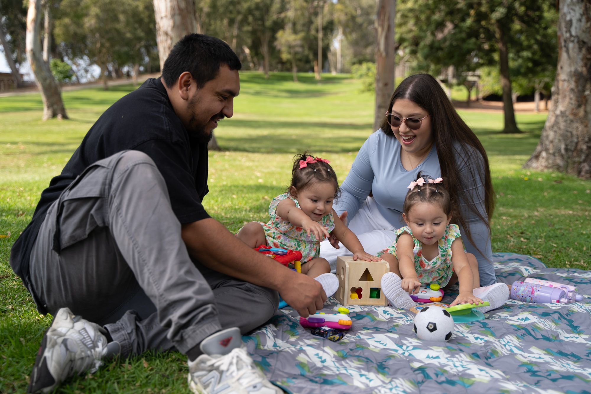 Ruby Esparza, who lives with MS, sits with her husband and her twin daughters in the park.