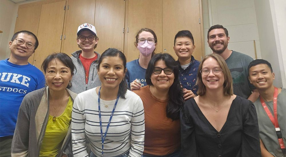 A group of 5 young adults and 5 adults pose together in a lab.