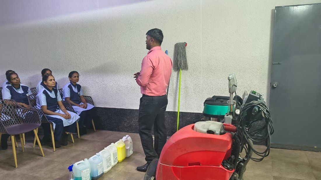 Whitehand trainer briefing housekeeping staff on cleaning chemicals and an auto scrubber during a training session in Bangalore