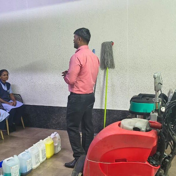 Whitehand trainer briefing housekeeping staff on cleaning chemicals and an auto scrubber during a training session in Bangalore