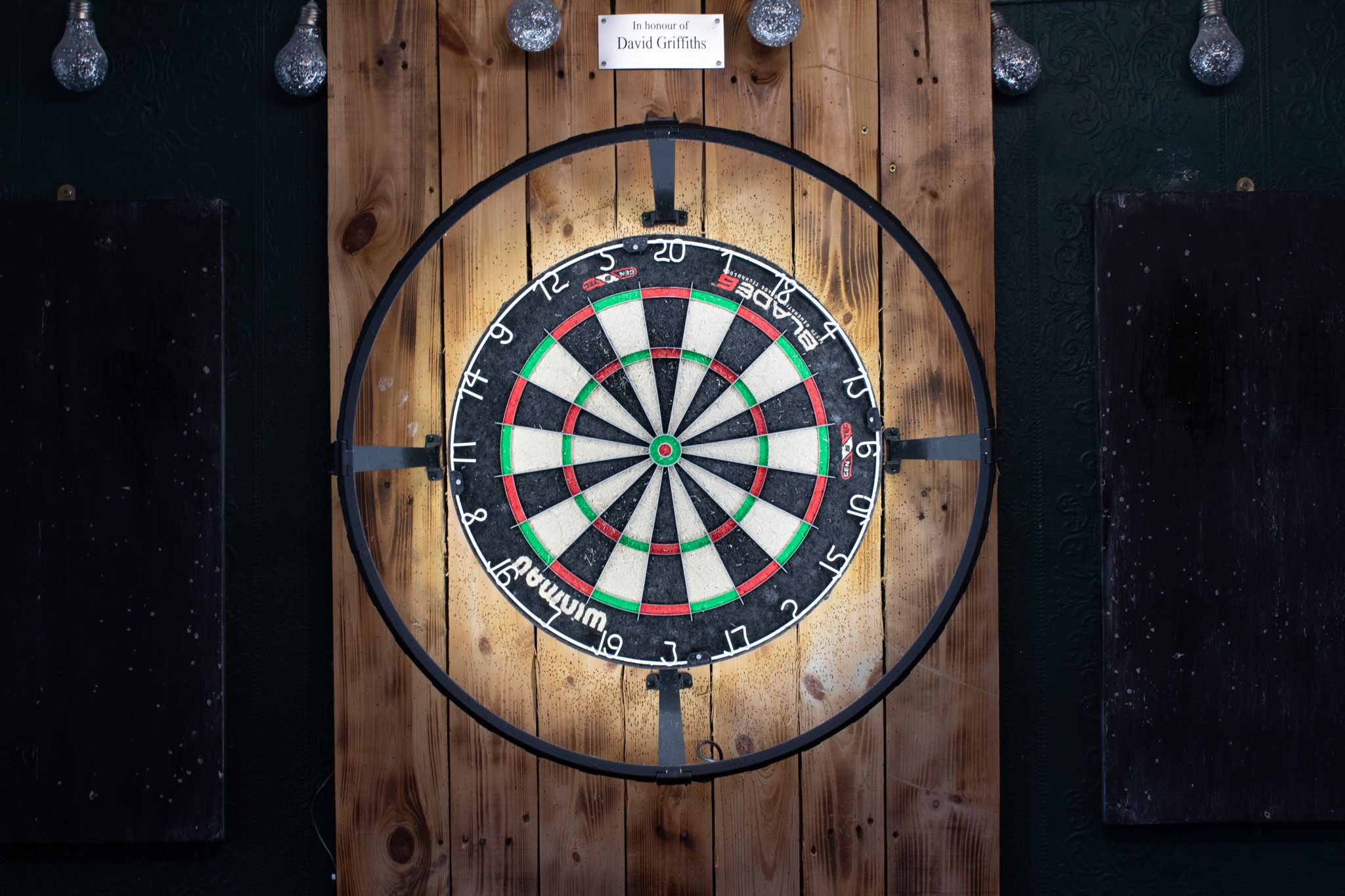 Dartboard in the games room, lit by a halo light.