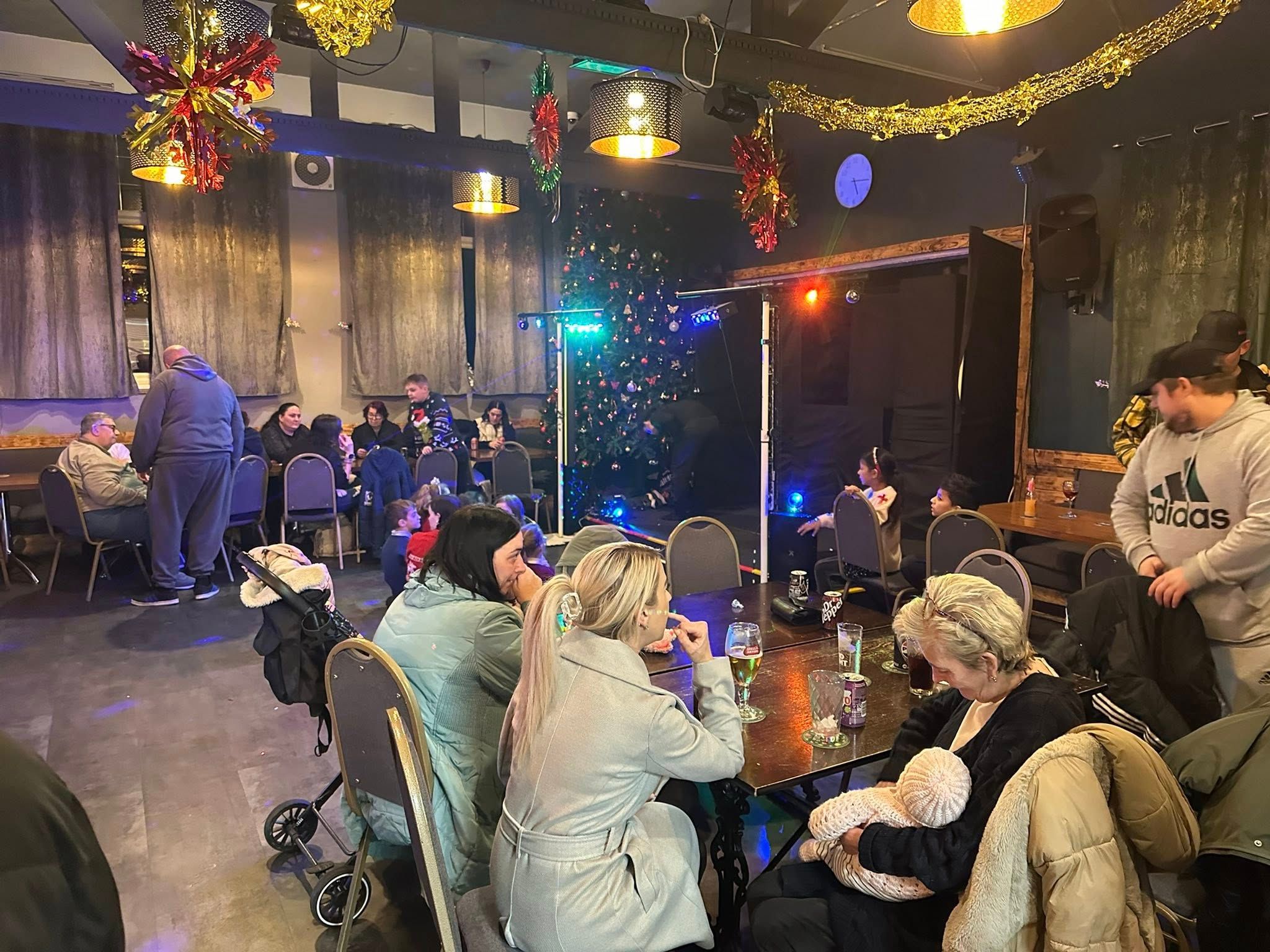 Families gathered inside The Crossings Club beside the UV puppet theatre and Christmas tree.