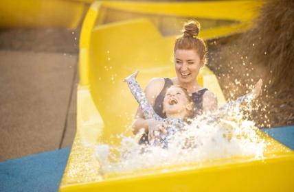 Mother and daughter laughing together as they splace at the end of the slide in Aquaplay area of Hanmer Pools