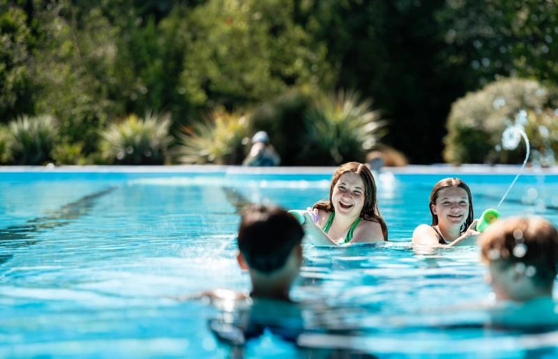 Four teenage children splashing and playing together in the freshwater pools