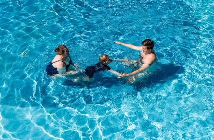 Family playing together and swim towards each other in activity pools Hanmer Springs