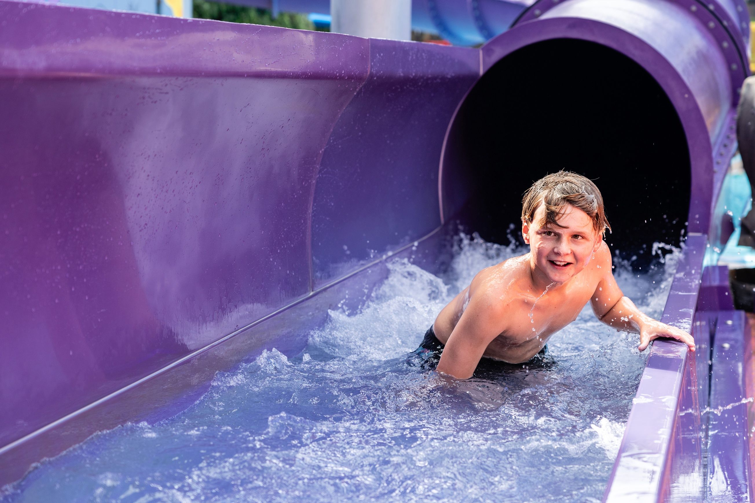 A young boy steps out of a purple hydroslide at Hanmer Springs