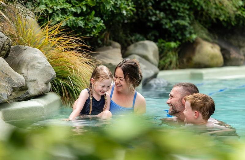 Young family smiling and enjoying time together in the community of Hanmer Springs surrounded by nature