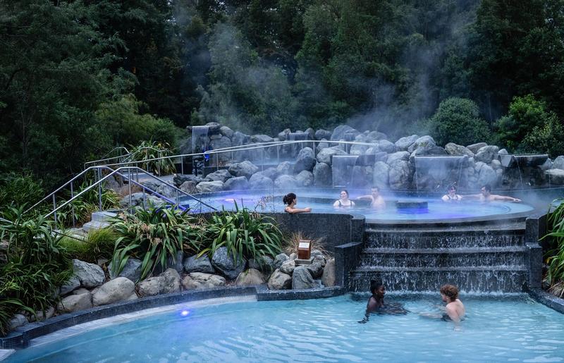 People in the termal pools amongst the steam and trees of the Cascade Pools relaxing and connecting in thermal pools at Hanmer Springs