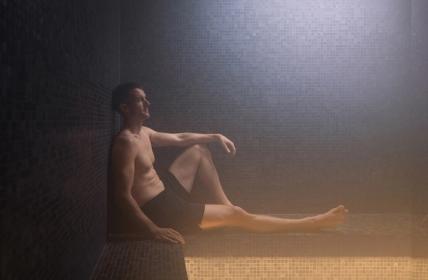Young man sitting against the wall with feel up in the Elemental Steam room