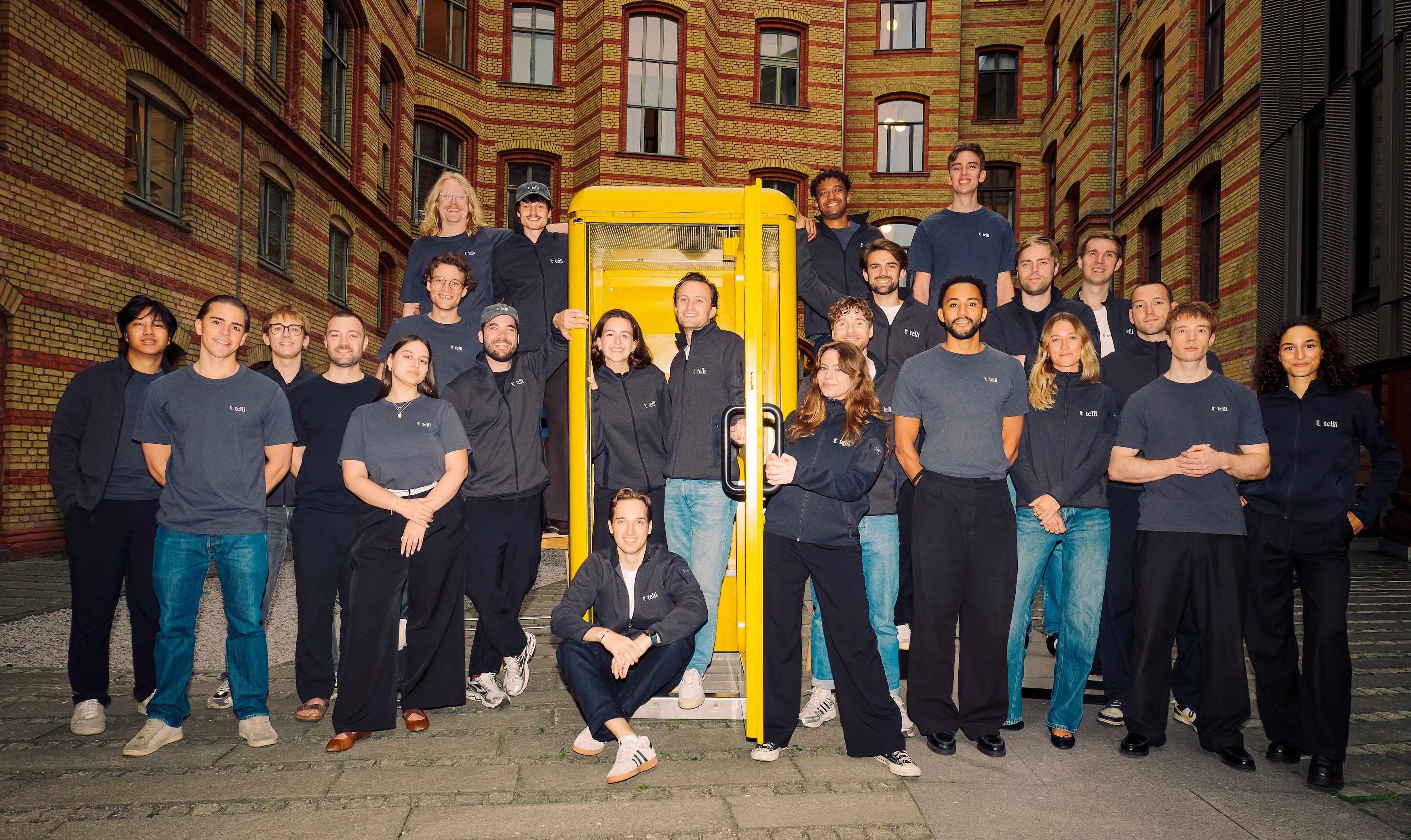 The telli team gathered around a yellow phone booth