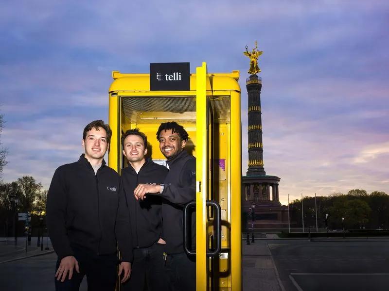 telli founders Seb, Finn, and Philipp in front of a yellow phone booth
