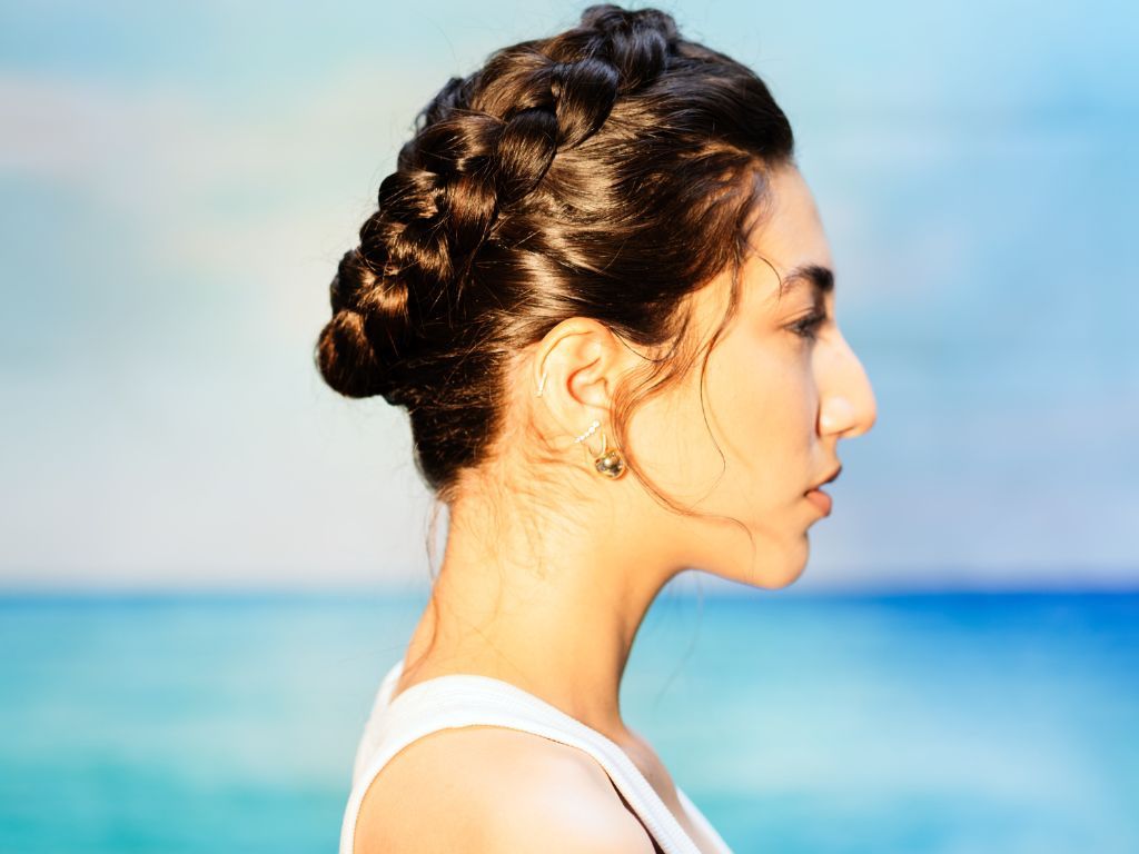 Model wearing a crown braid hairstyle, showcasing a protective summer look that keeps hair secure, elegant, and frizz-free