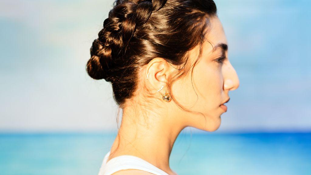 Model wearing a crown braid hairstyle, showcasing a protective summer look that keeps hair secure, elegant, and frizz-free