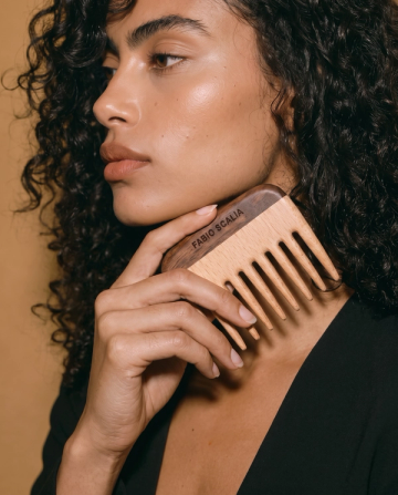 Curly hair woman holding wooden comb