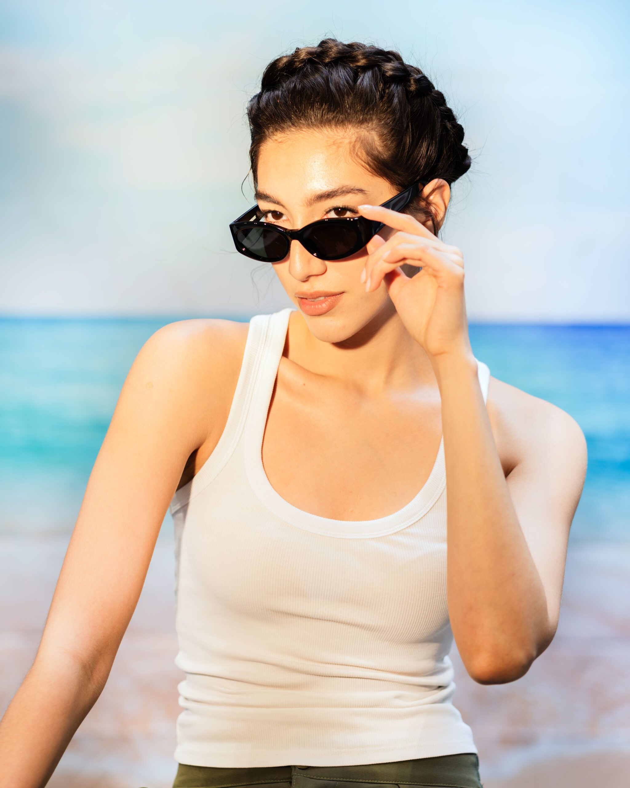 Model at the beach wearing crown braids, a protective summer hairstyle that keeps hair secure, stylish, and frizz-free