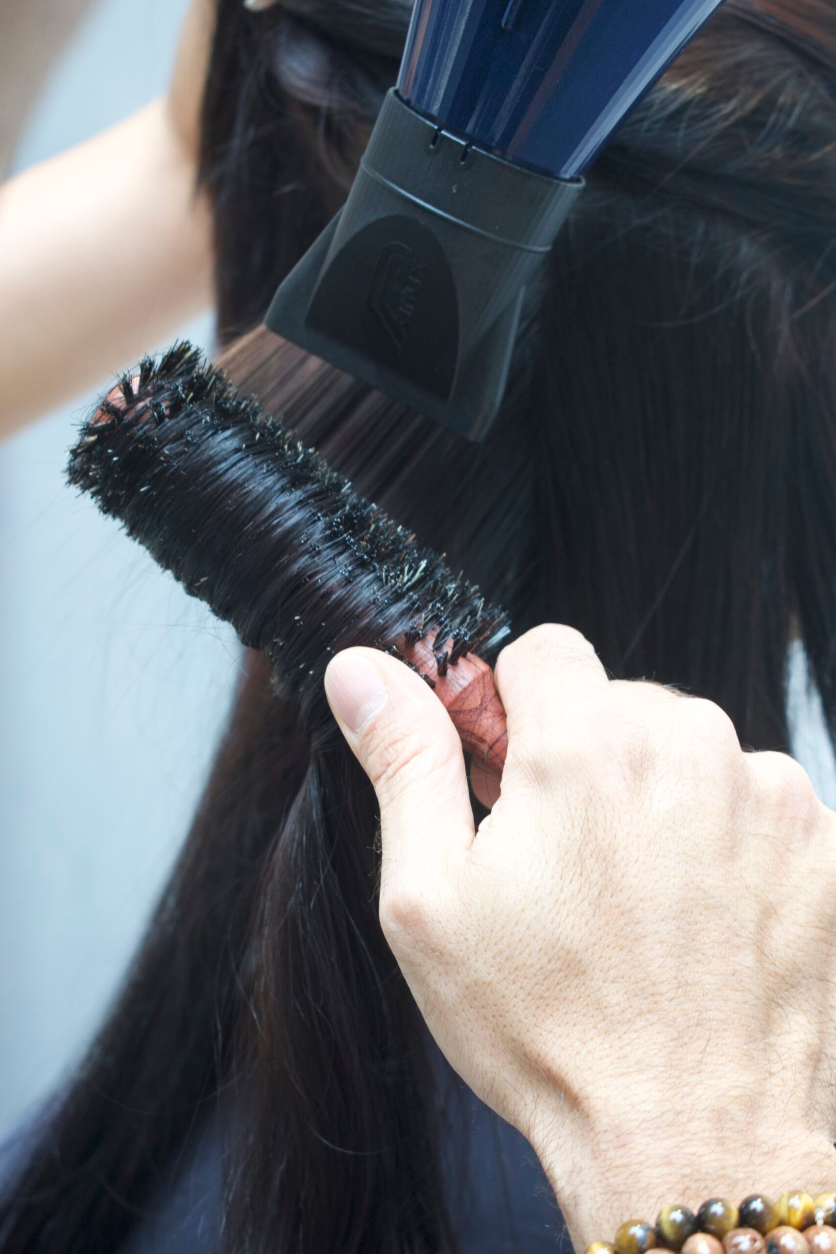 Close-up of brush and blow dryer nozzle working together to smooth and style hair.