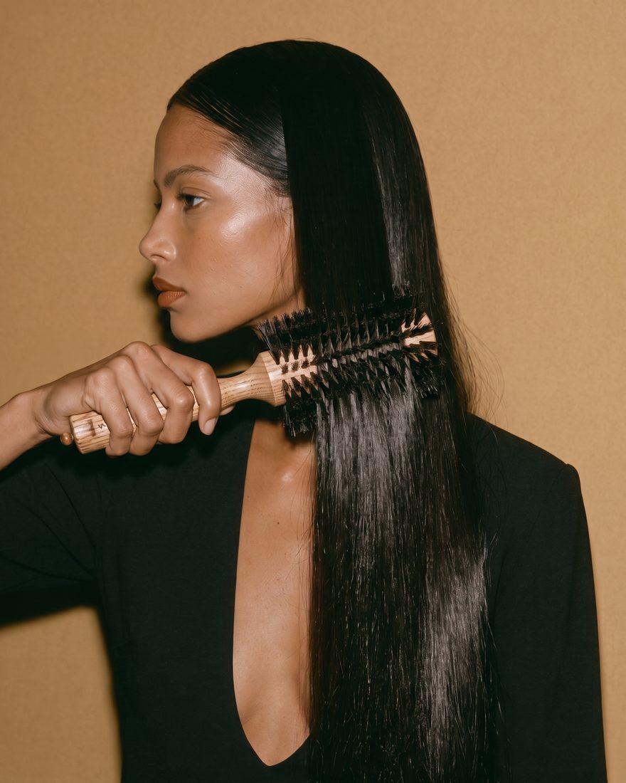 Model styling long, sleek hair with a Fabio Scalia round brush