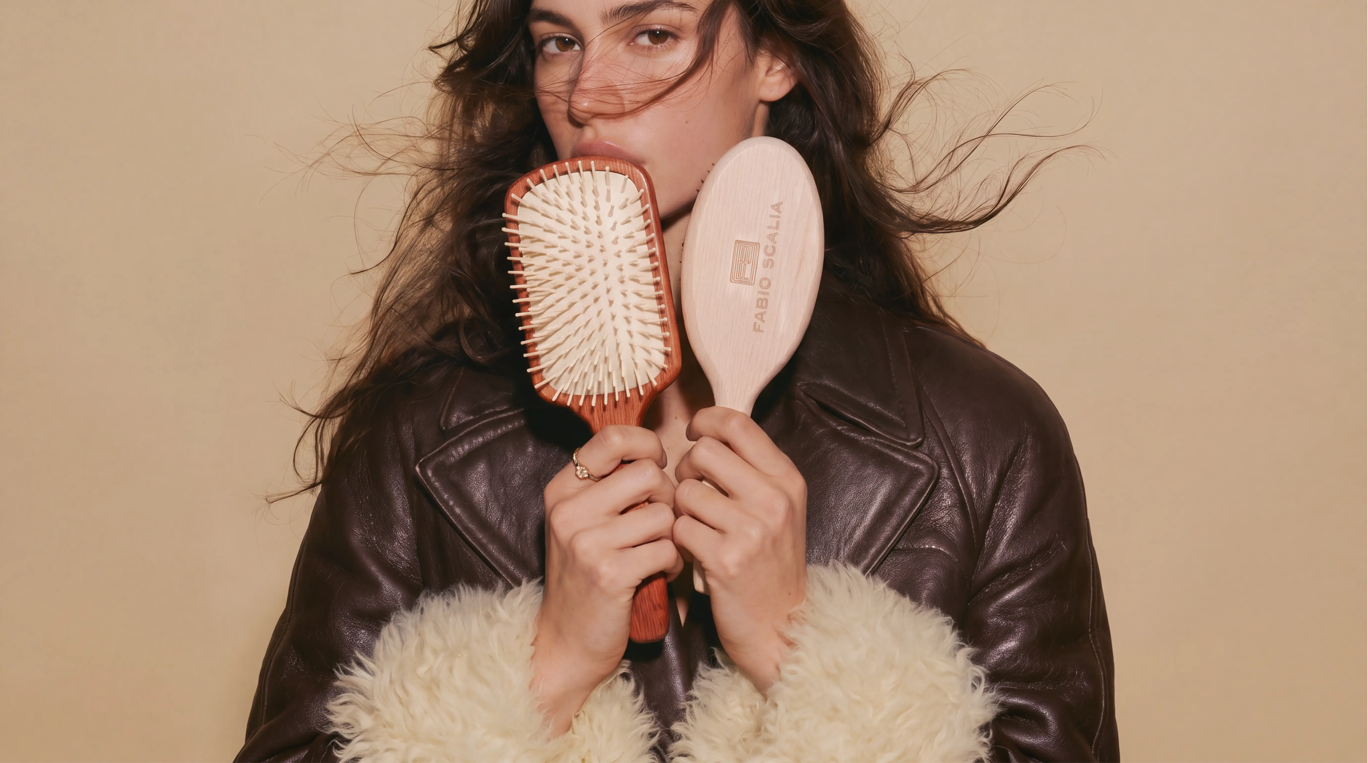Model in a leather jacket holding two Fabio Scalia hair brushes