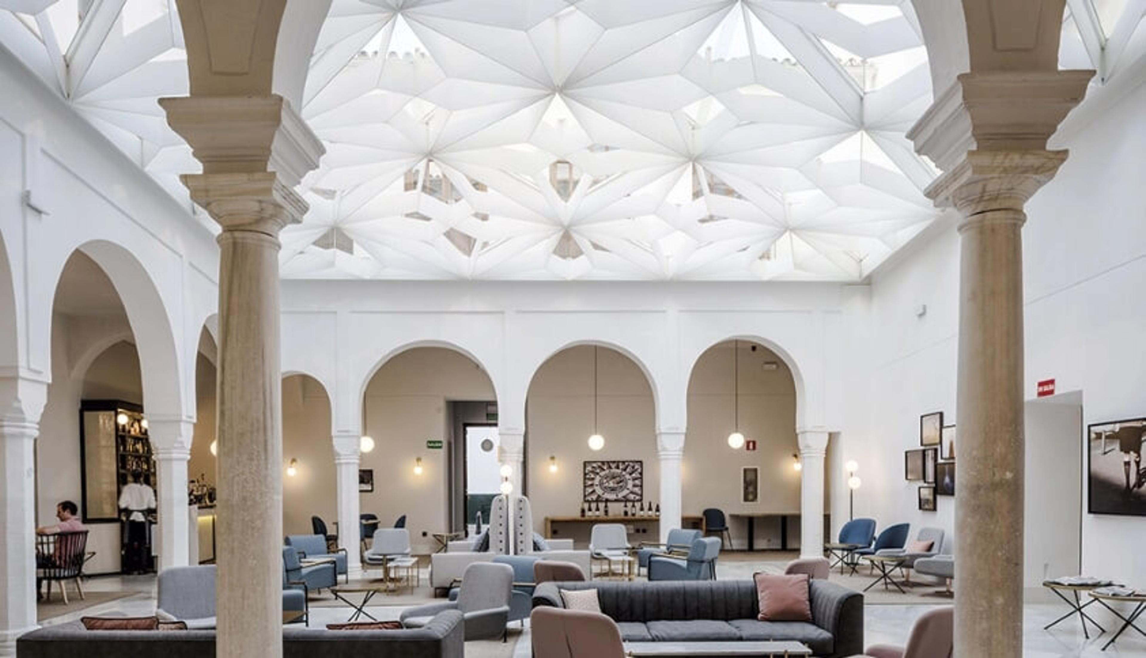 The covered patio at Lalola, arches round tables under a glass roof