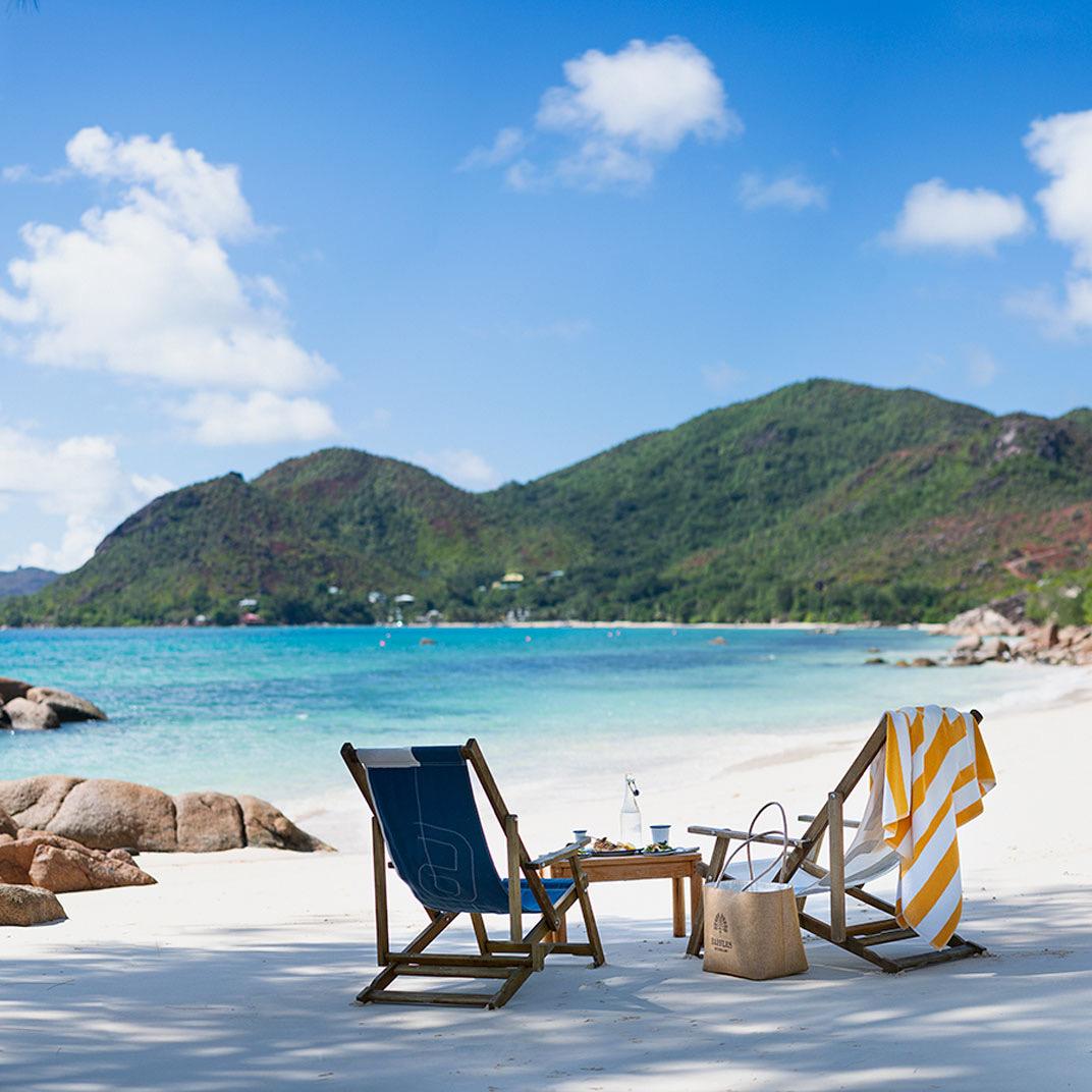 Loungers on a white beach between granite boulders