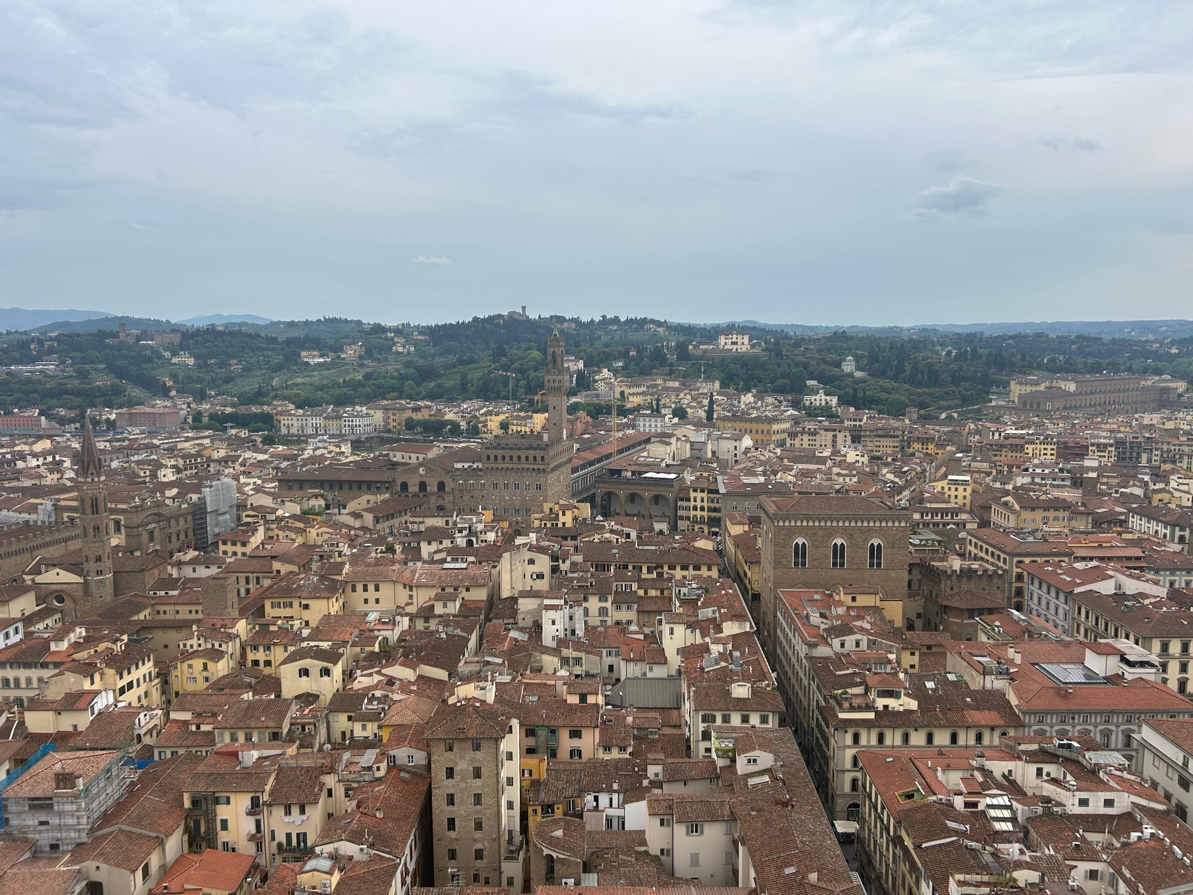 Florence's terracotta rooftops from Giotto's bell tower, with the tower of the Palazzo Vecchio and the hills south of the Arno beyond
