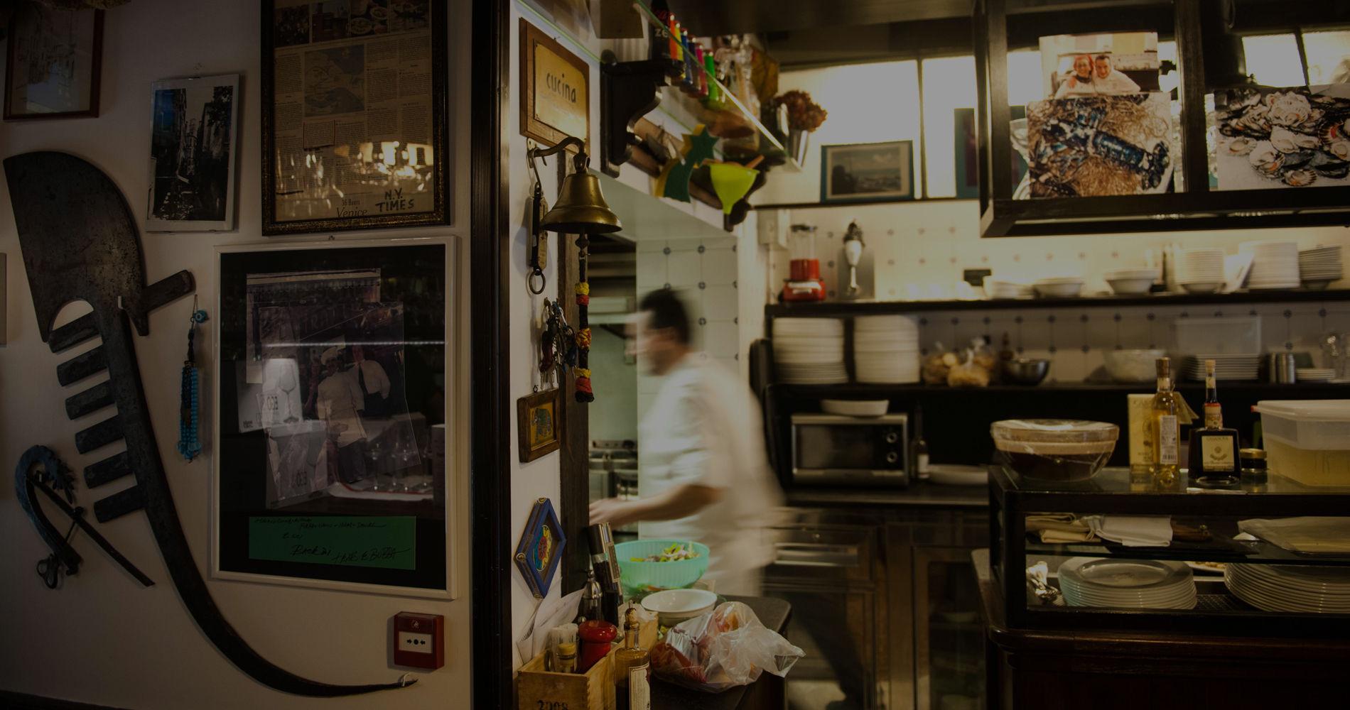 A narrow, dimly lit dining room with framed pictures on the walls