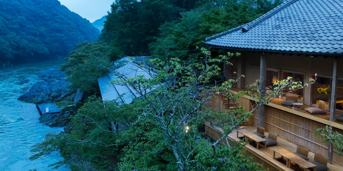 The hotel's tiled roofs and wooden terraces among trees above the river gorge