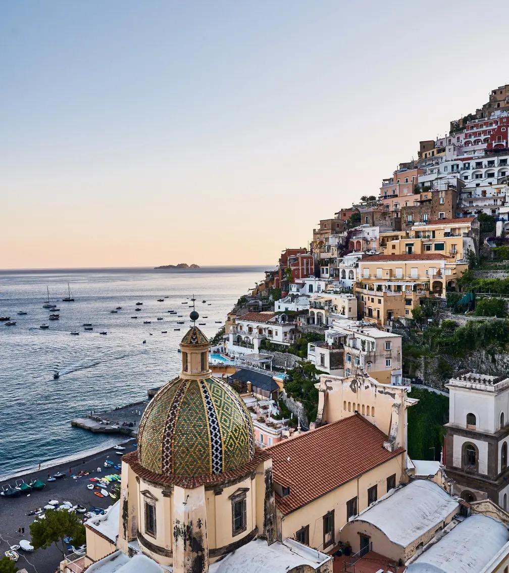 Positano's houses stacked up the cliff above the sea, the tiled dome of the church in the foreground.