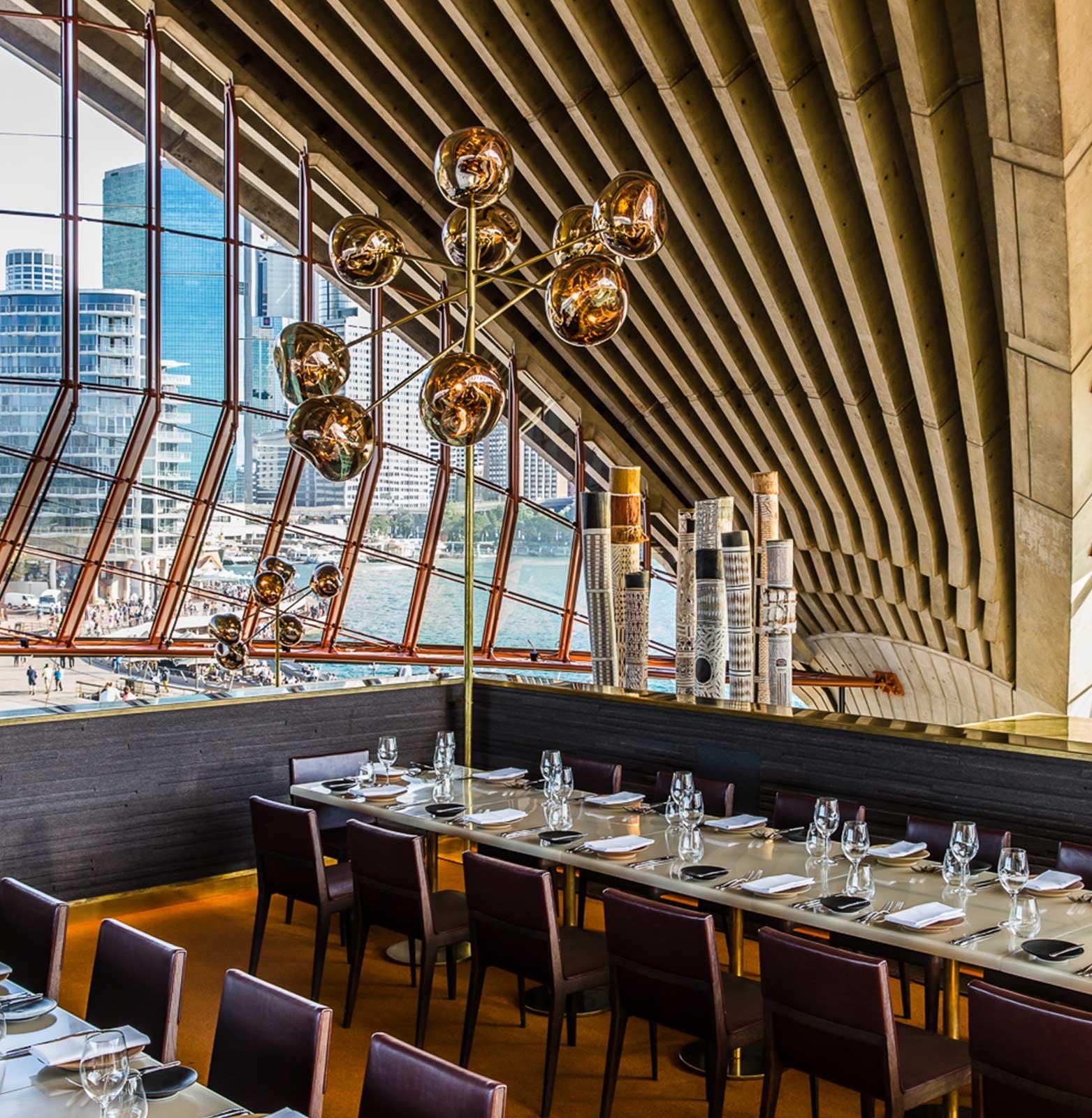 Tables laid beneath the ribbed concrete vaults of an Opera House sail