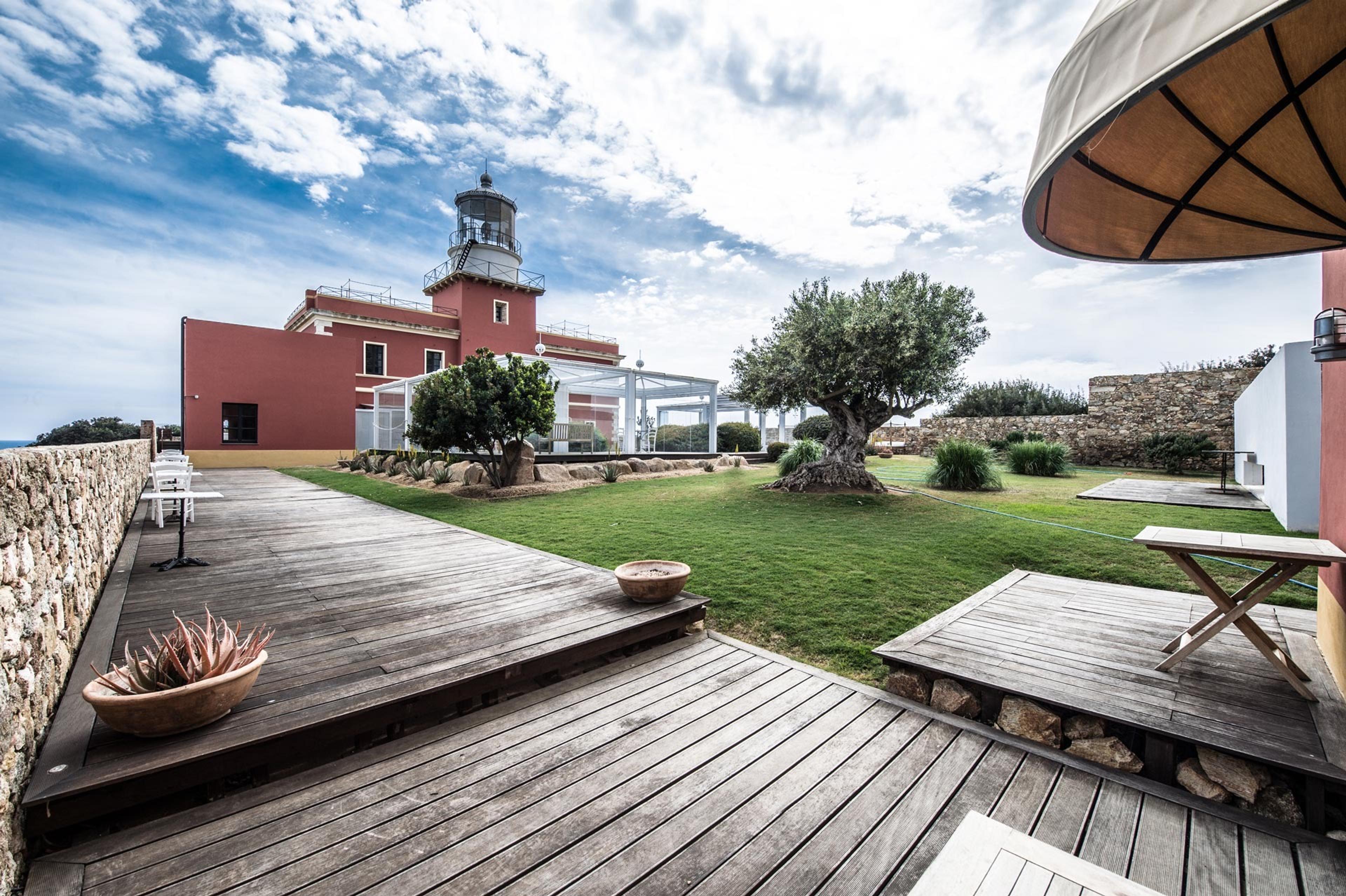 The red lighthouse keeper's building and its lawn and deck at Capo Spartivento