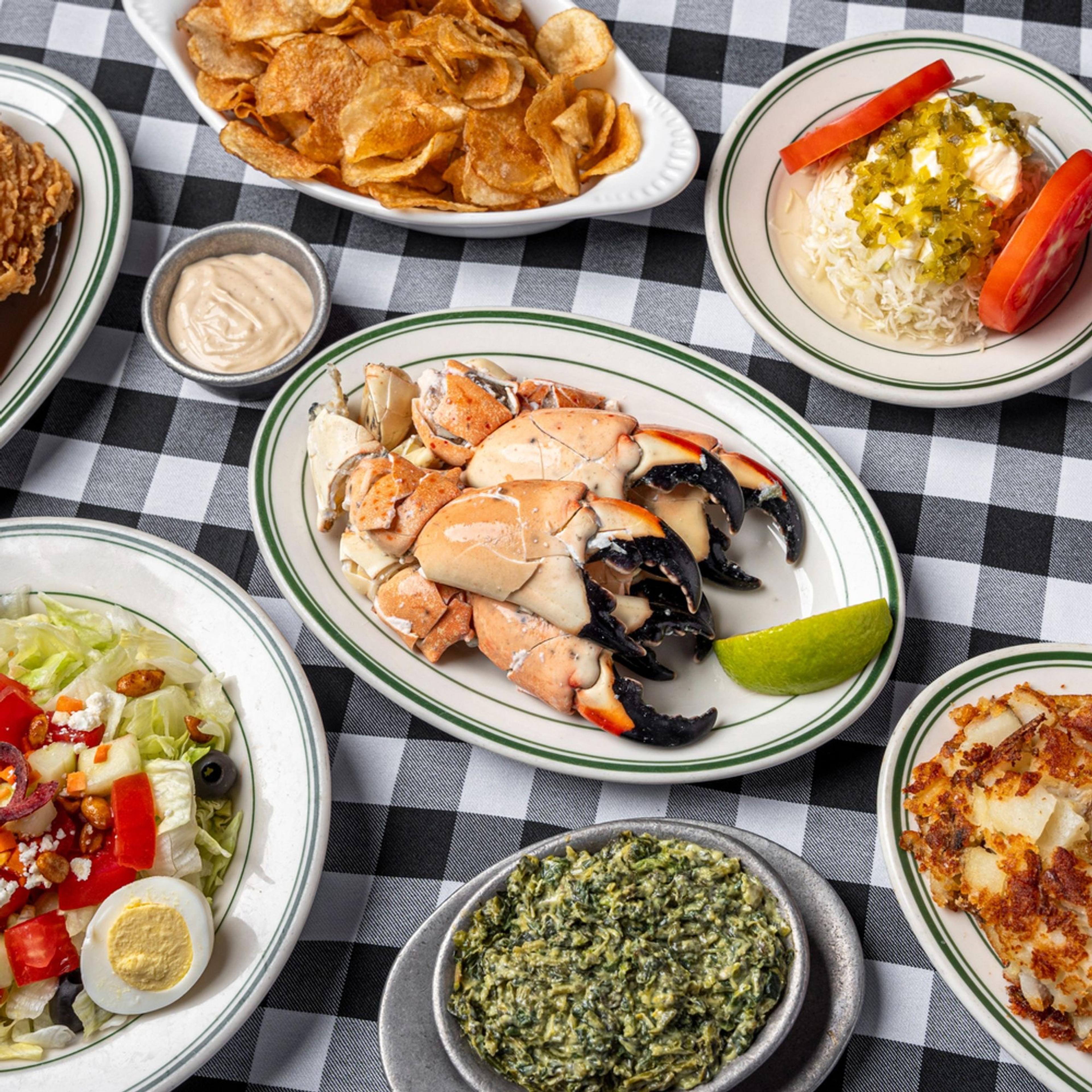 A platter of stone crab claws with lime on a checked tablecloth