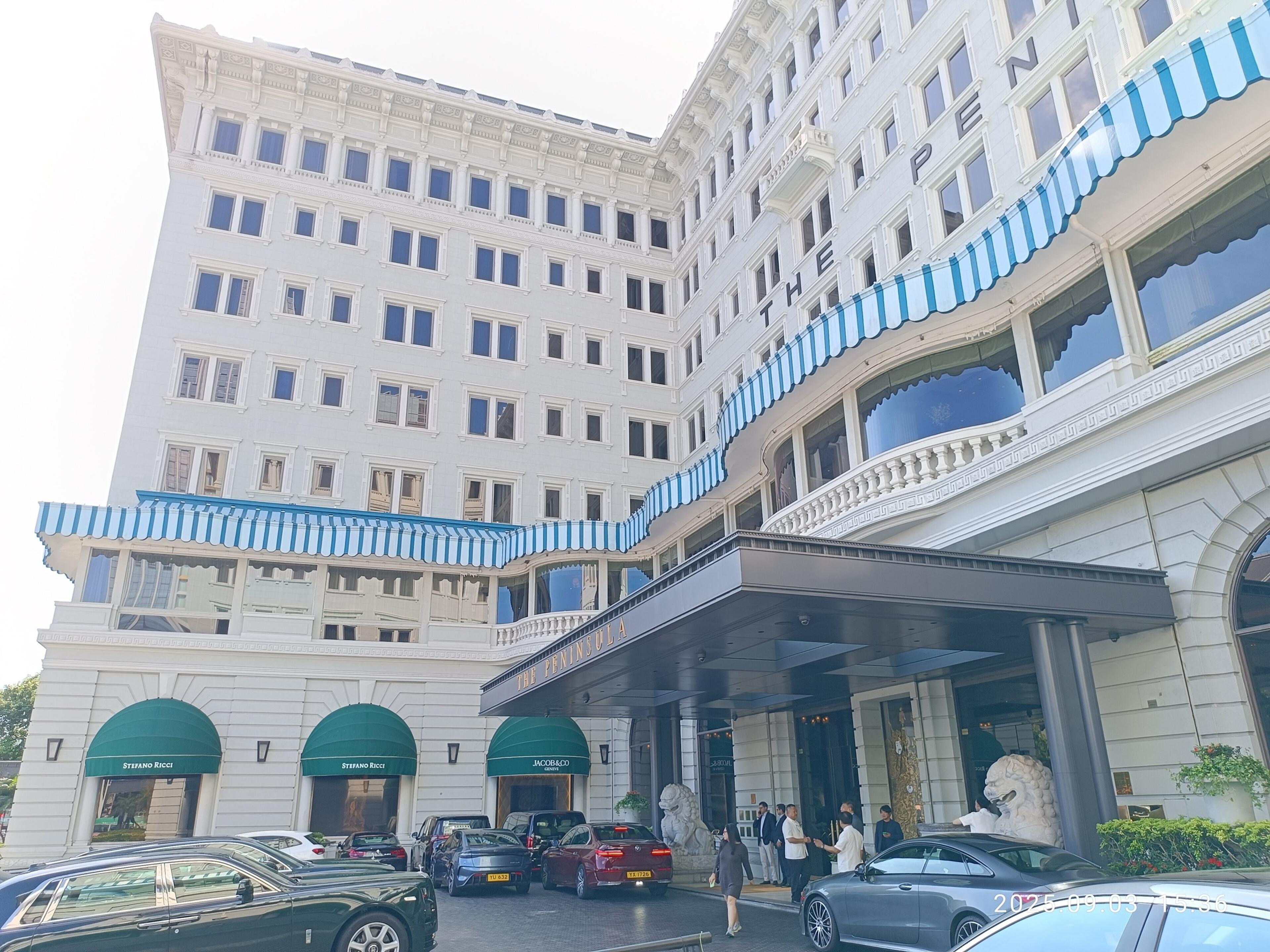 The white hotel and its later tower above the forecourt, with green awnings at street level