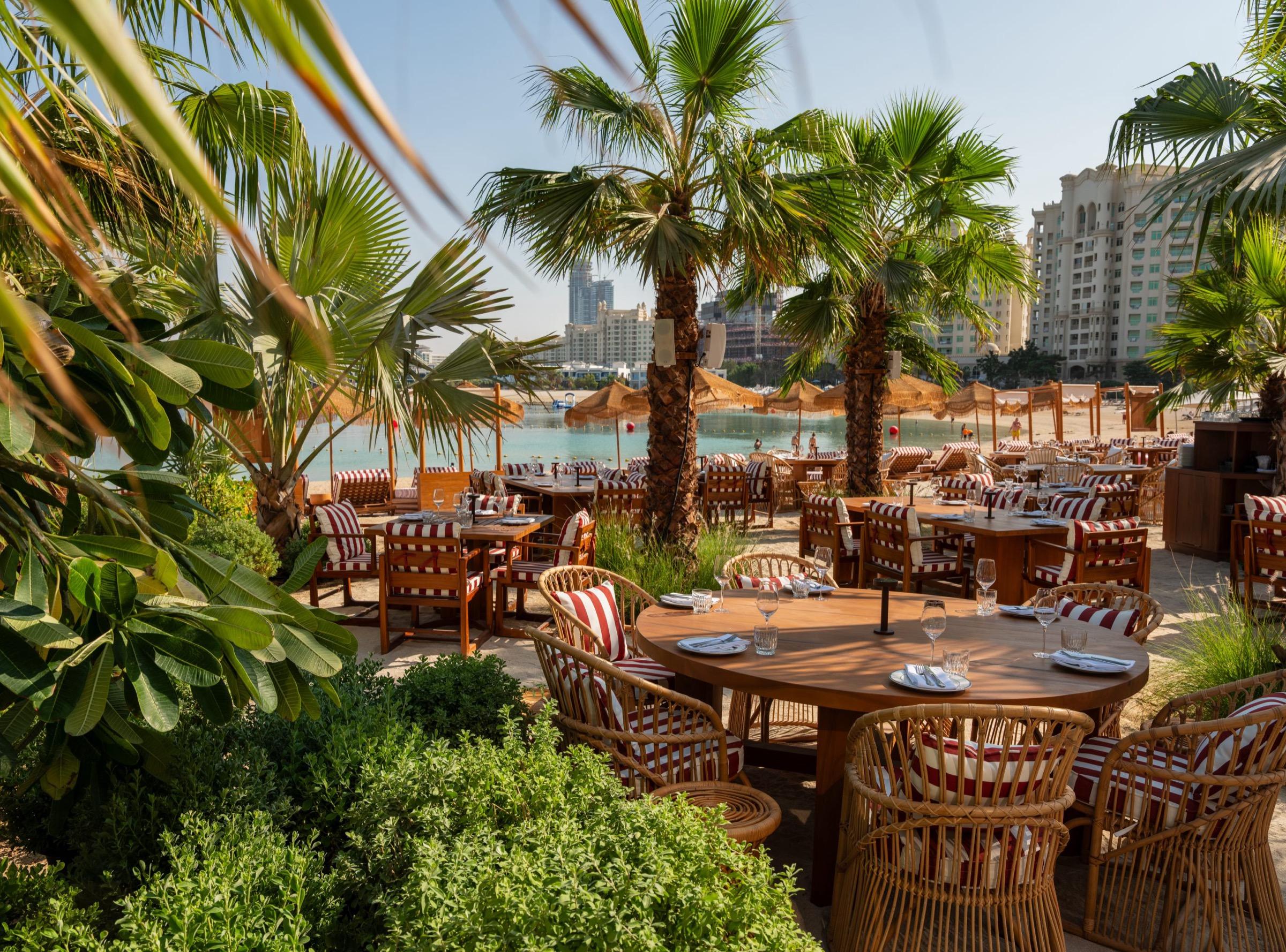 Tables among palms on the garden terrace at The Maine Beach House