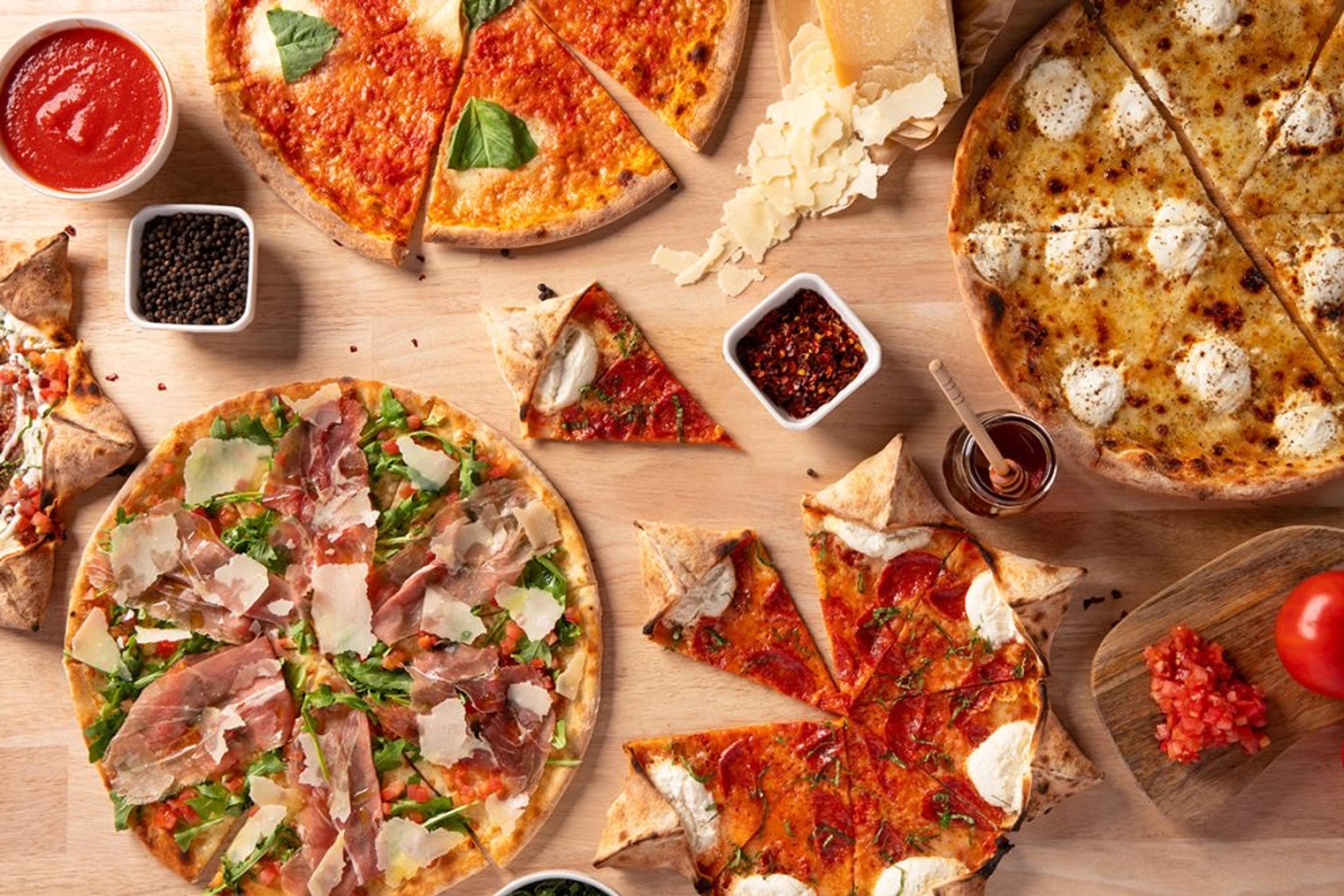 Pizzas spread across a wooden table, one with a star-shaped crust
