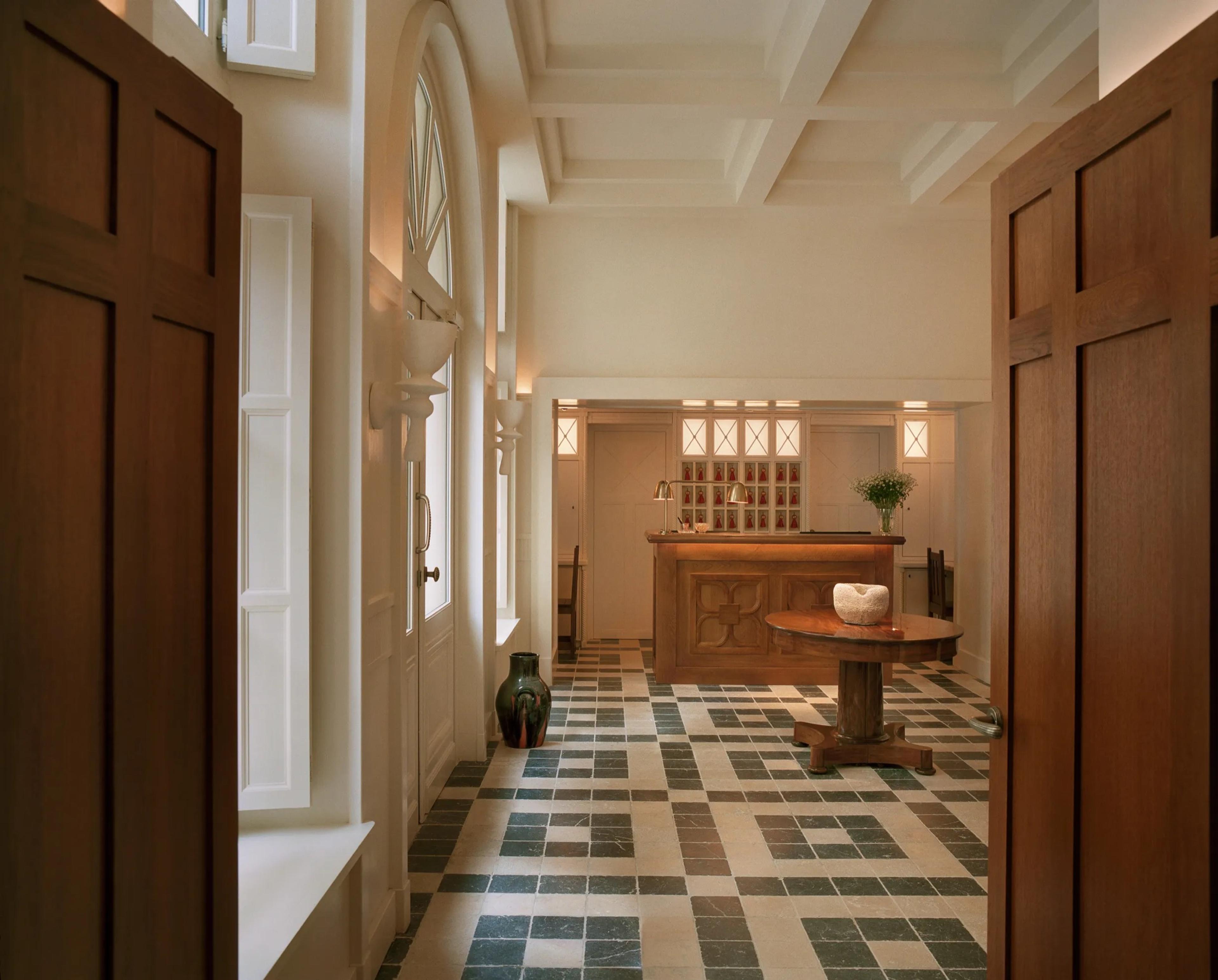 An entrance hall seen through a pair of panelled doors, its floor tiled in blue and white.