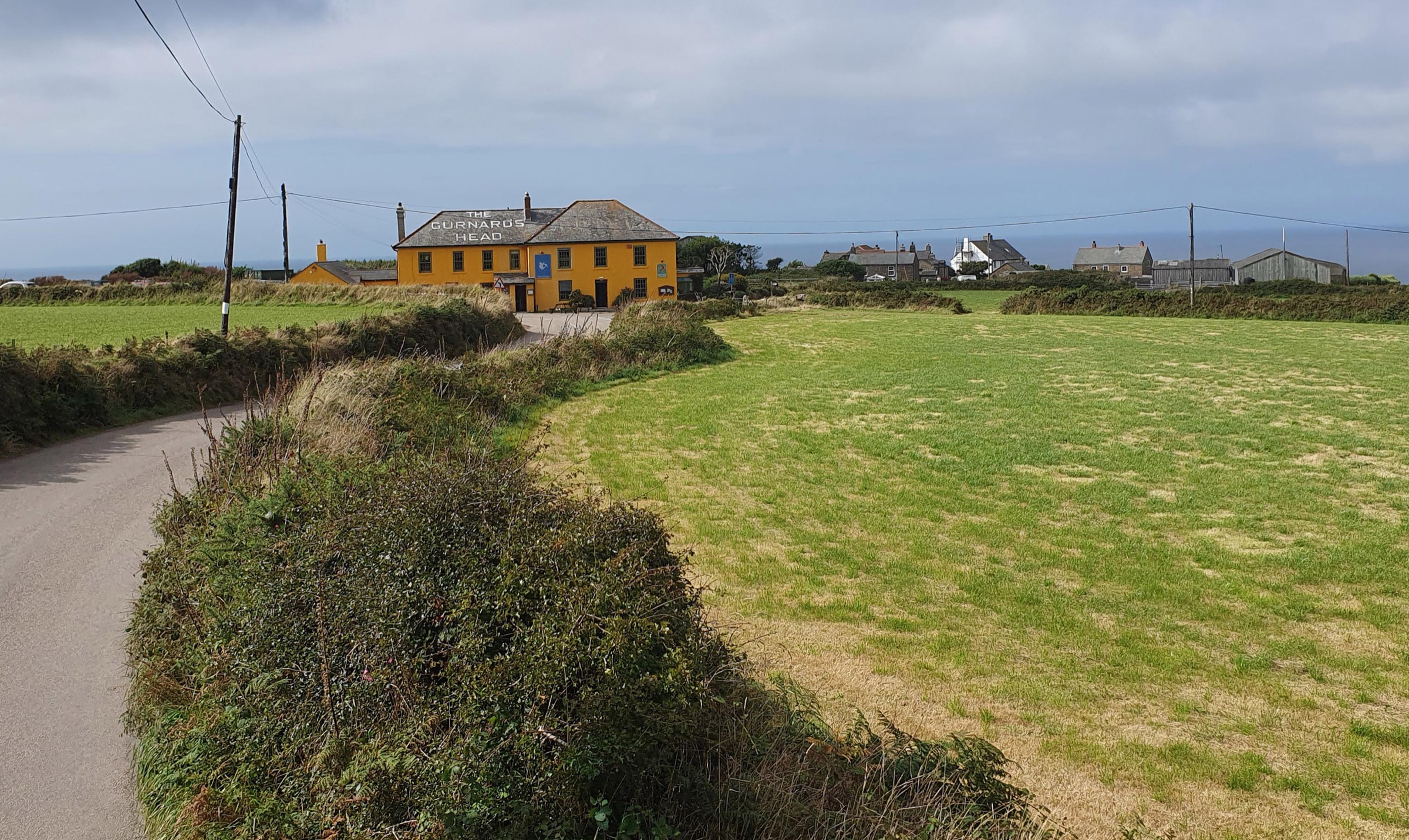 The yellow inn standing on its own across green fields and hedges.