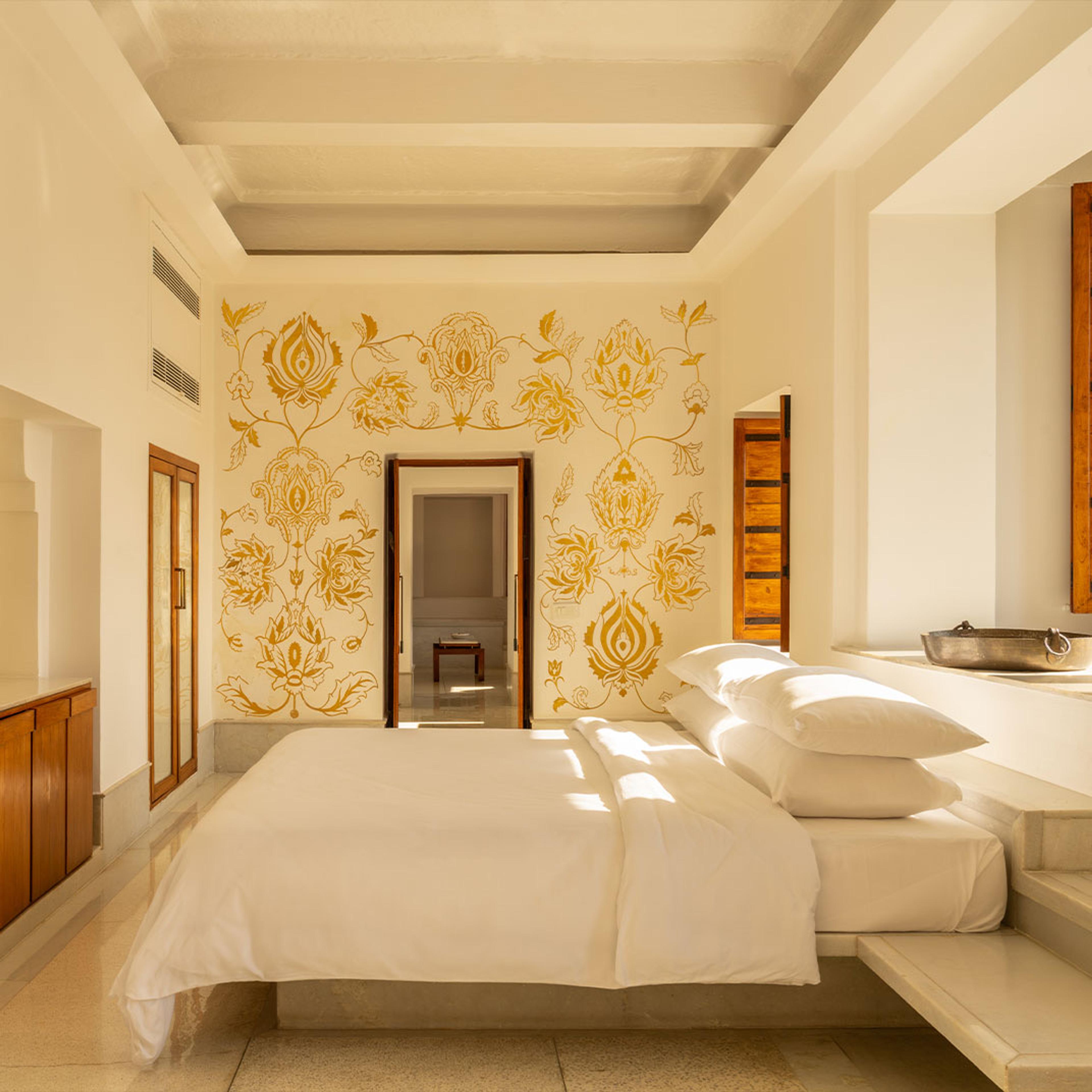 A white suite with a carved wall behind the bed