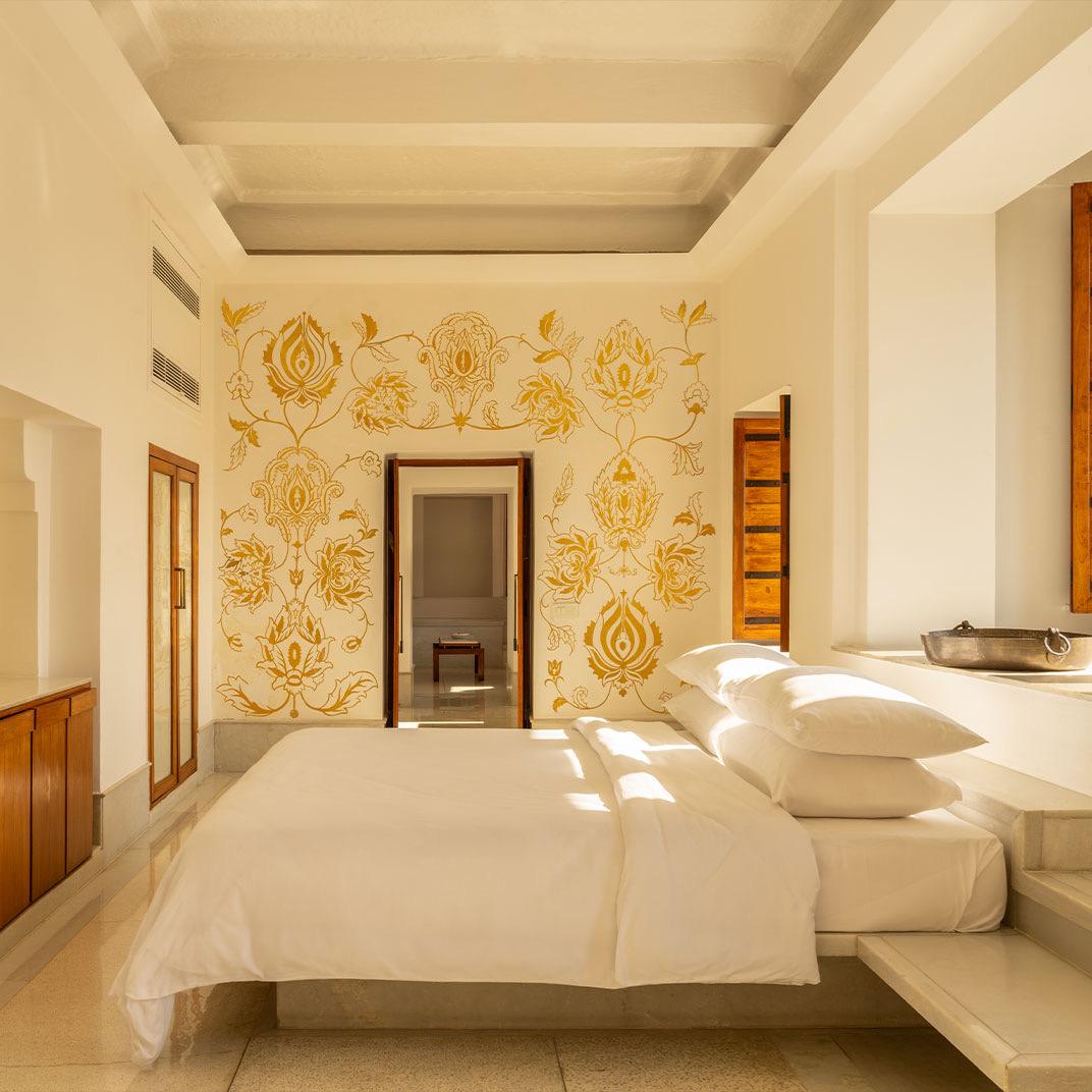 A white suite with a carved wall behind the bed