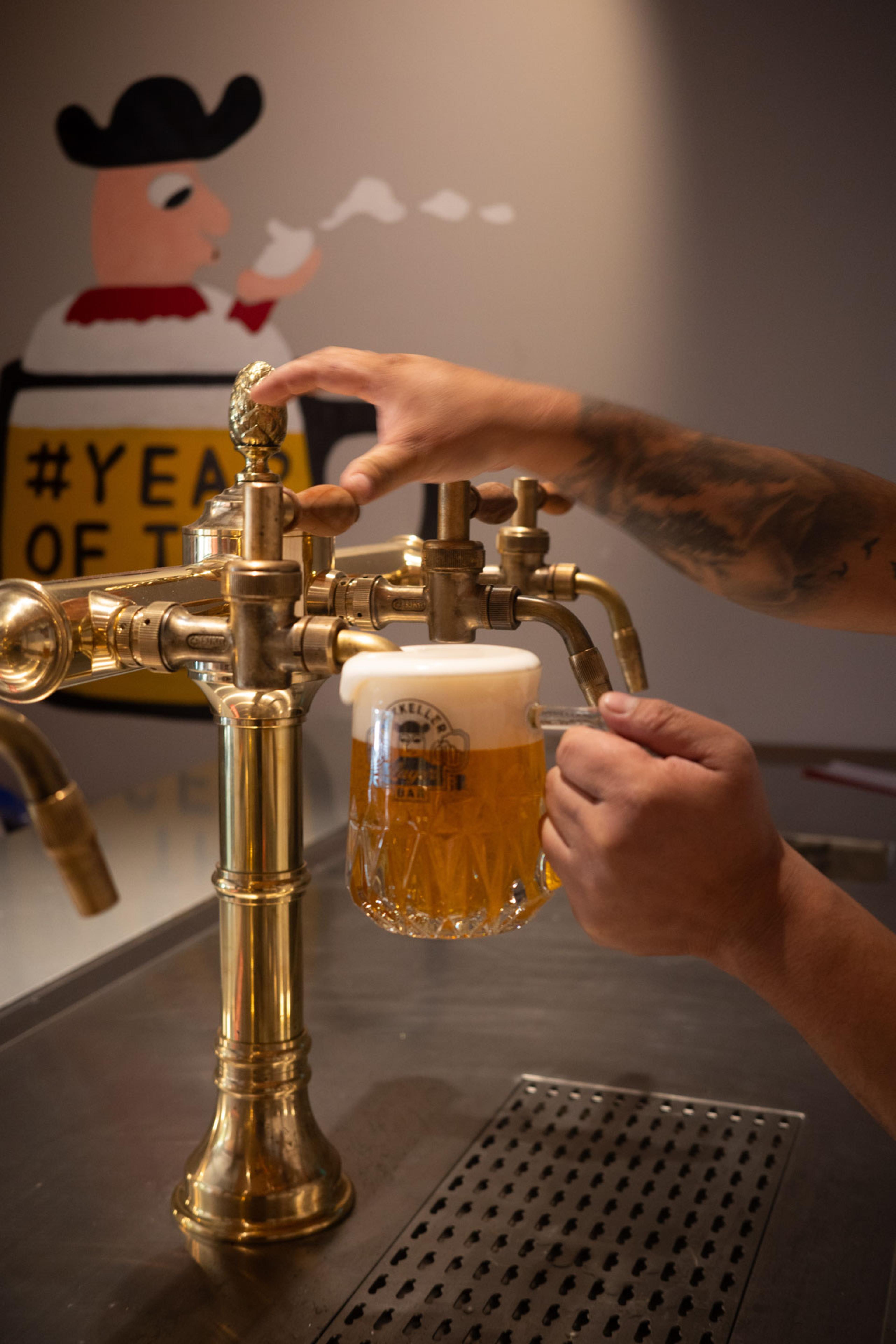 A Mikkeller beer being poured from a brass tap into a dimpled glass mug