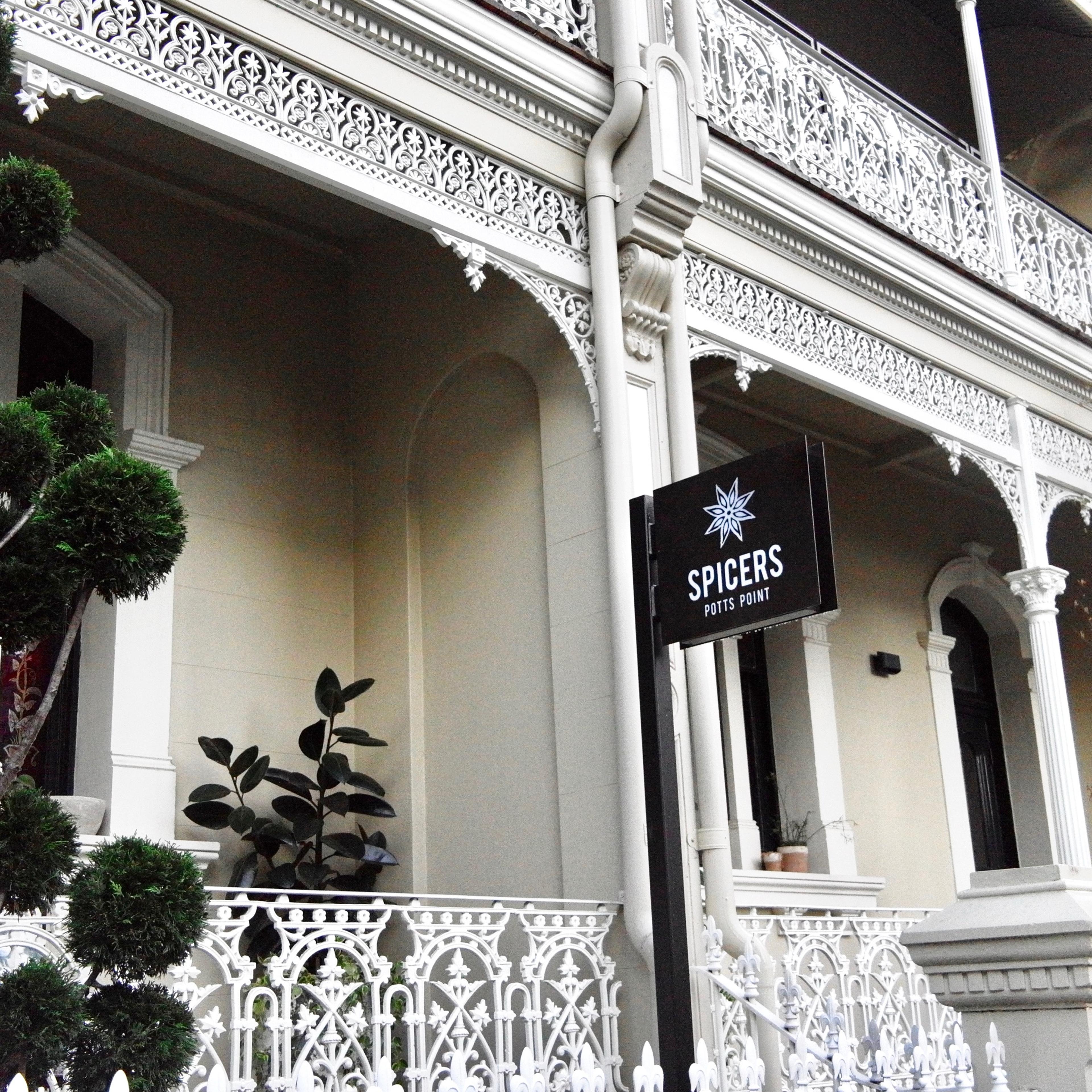 The hotel's entrance beneath the iron lacework of a Victorian terrace, with its sign beside the door