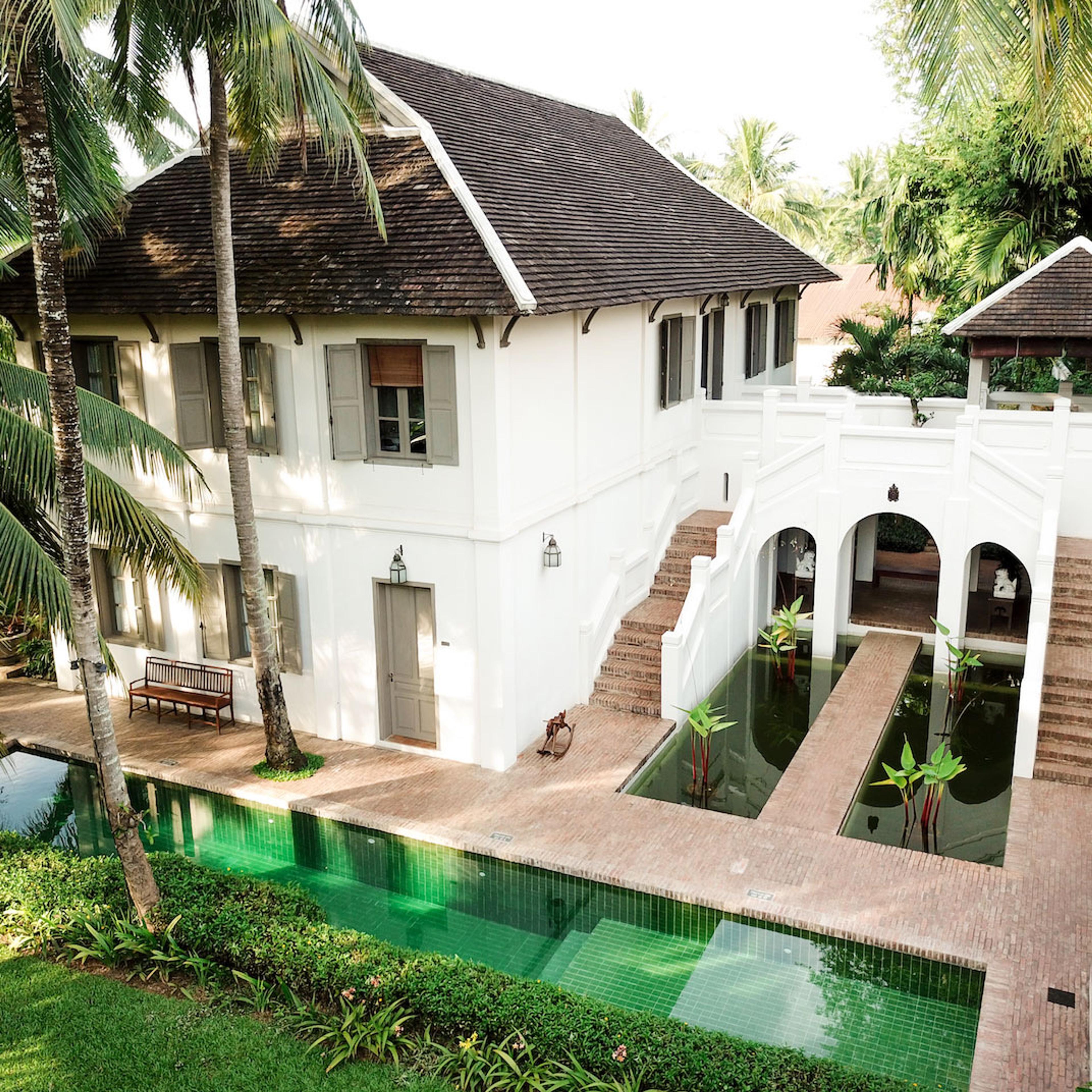 A white house with steps down to a green-tiled pool