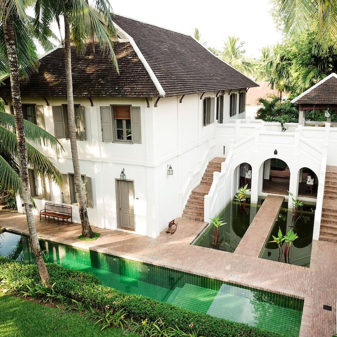 A white house with steps down to a green-tiled pool